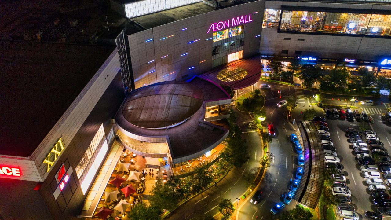 Illuminated aerial view of Aeon Mall in Banten, Indonesia, featuring a bustling parking lot at night.